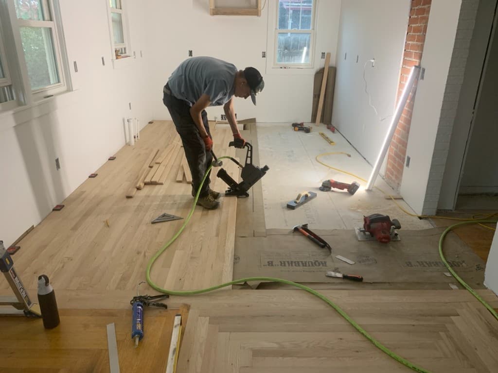 Craftsman installing hardwood flooring with pneumatic nailer