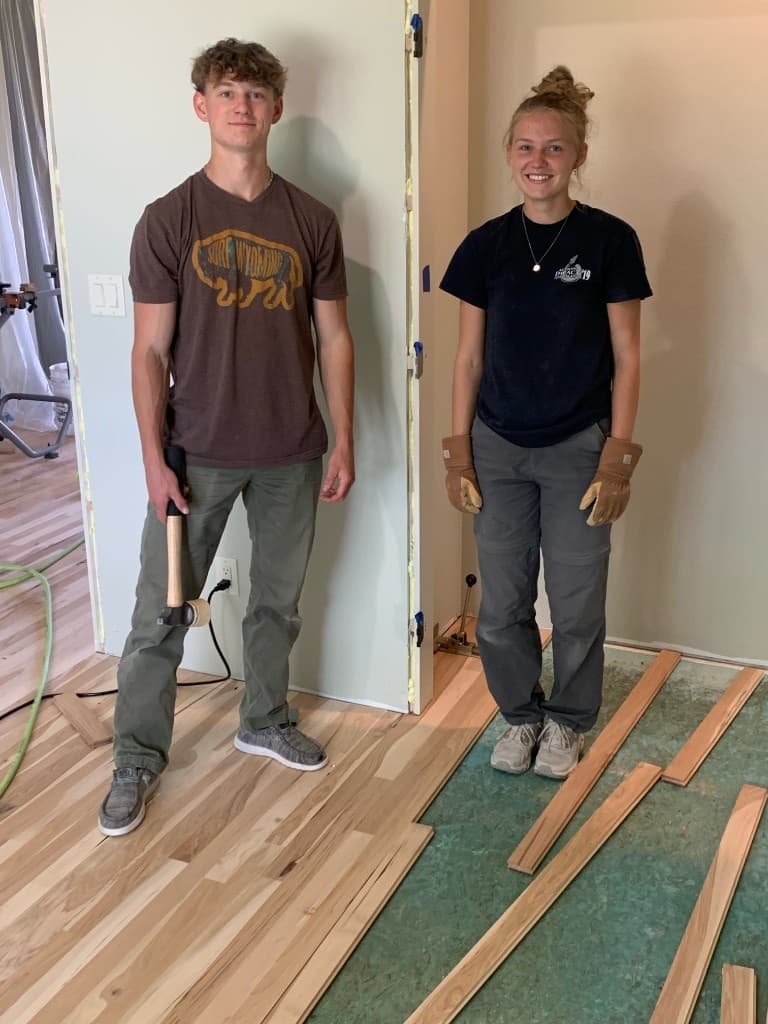 Stevenson family members installing hardwood flooring on a job site