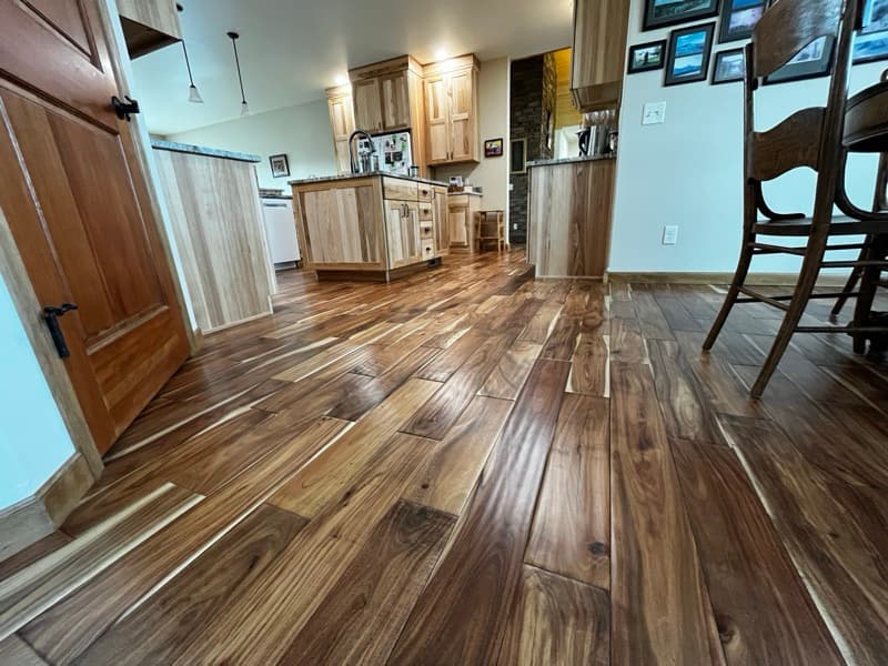 Newly installed hardwood floor beside a stone fireplace in a Cody, Wyoming home